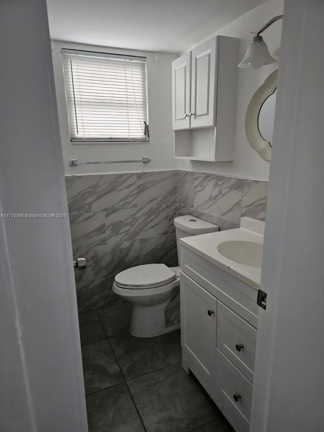 bathroom with vanity, tile walls, tile patterned floors, and toilet