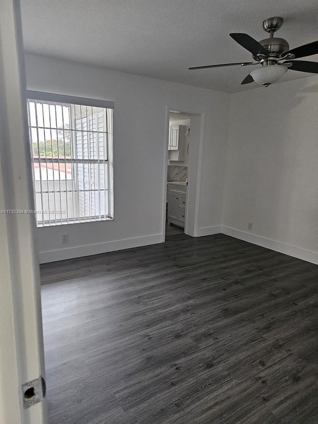 empty room featuring ceiling fan, dark hardwood / wood-style flooring, and a textured ceiling