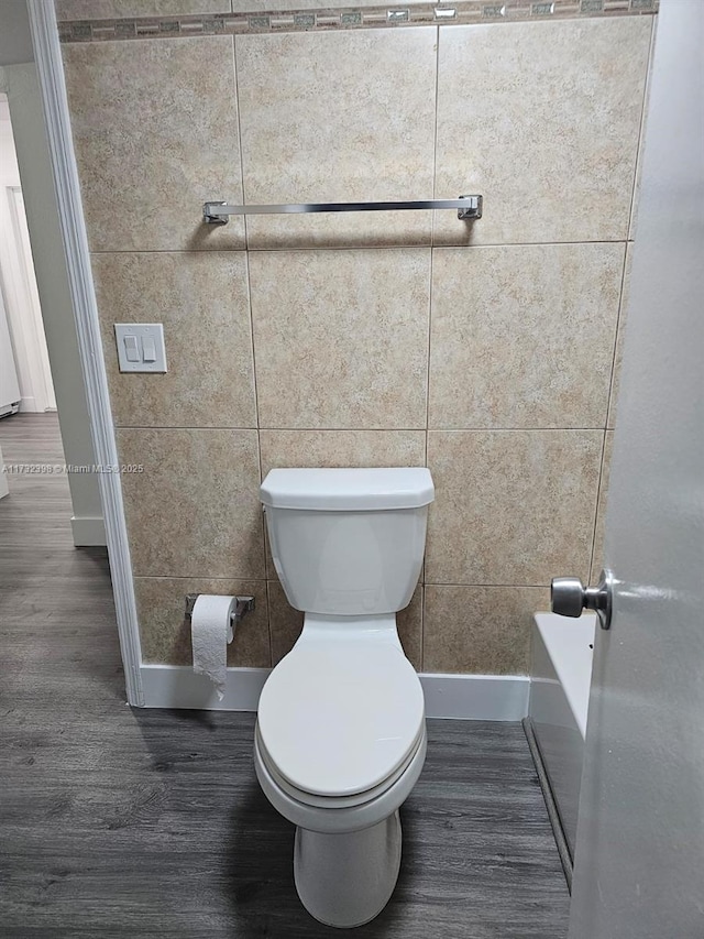 bathroom featuring toilet, hardwood / wood-style floors, and tile walls