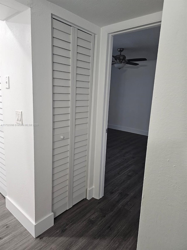 hall featuring dark wood-type flooring and a textured ceiling