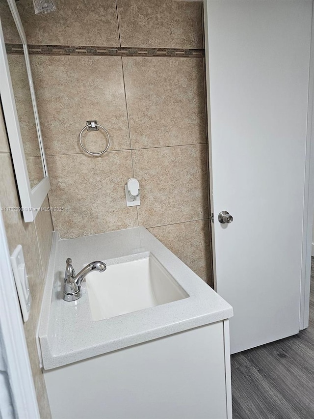 bathroom featuring hardwood / wood-style flooring, vanity, and tile walls