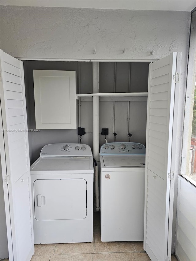 laundry room with separate washer and dryer, light tile patterned floors, and cabinets