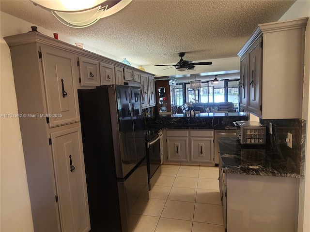 kitchen featuring light tile patterned flooring, black fridge, a textured ceiling, kitchen peninsula, and stove