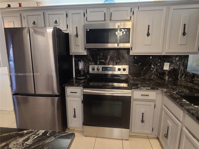 kitchen with stainless steel appliances, dark stone countertops, light tile patterned floors, and decorative backsplash