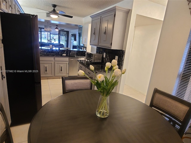 tiled dining area with ceiling fan and a textured ceiling