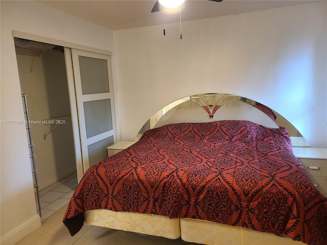 tiled bedroom with ceiling fan and a closet