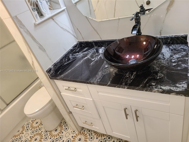 full bathroom with combined bath / shower with glass door, sink, and toilet