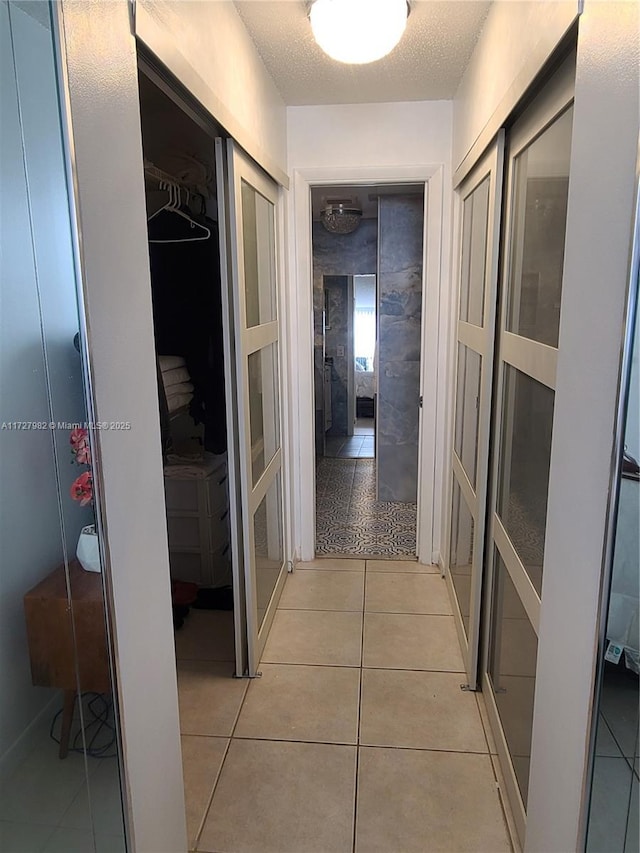 hallway with light tile patterned floors and a textured ceiling