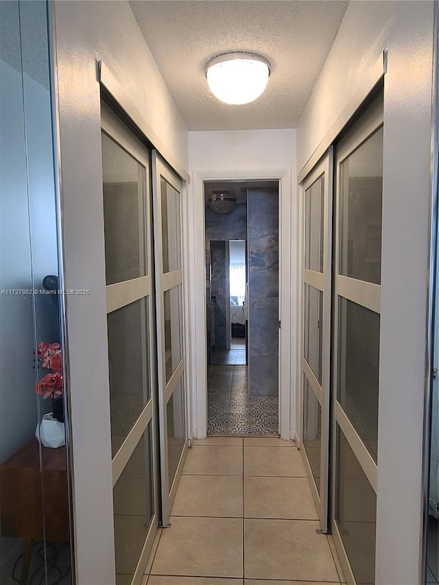 corridor with a textured ceiling and light tile patterned floors