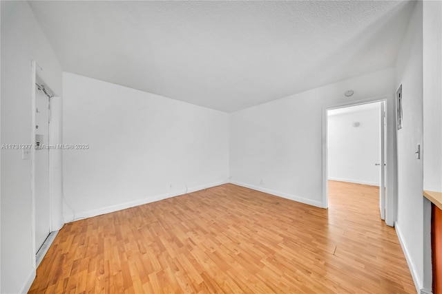 empty room with a textured ceiling and light wood-type flooring