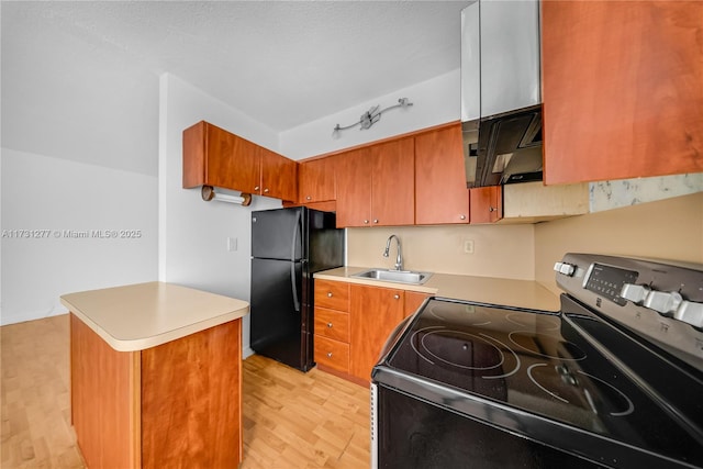 kitchen with sink, stainless steel range with electric cooktop, black fridge, light wood-type flooring, and kitchen peninsula