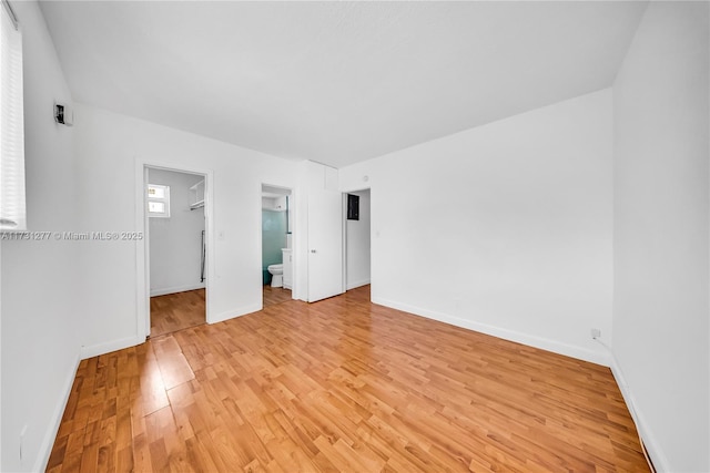 unfurnished bedroom with a spacious closet, light hardwood / wood-style flooring, a closet, and ensuite bathroom