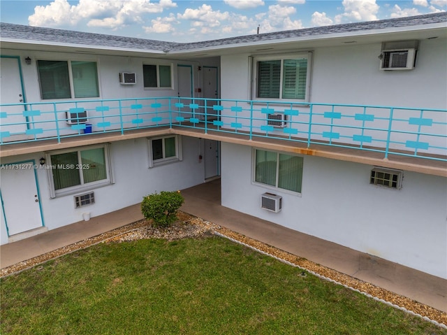 rear view of property with a yard and a wall unit AC