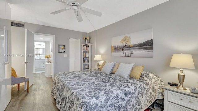 bedroom featuring ensuite bath, light hardwood / wood-style flooring, and ceiling fan