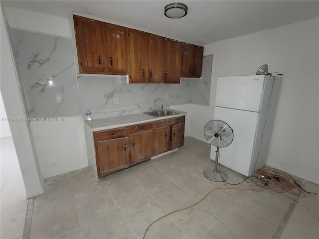 kitchen with white refrigerator, sink, and backsplash