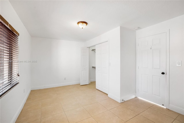 unfurnished bedroom featuring light tile patterned floors and a closet