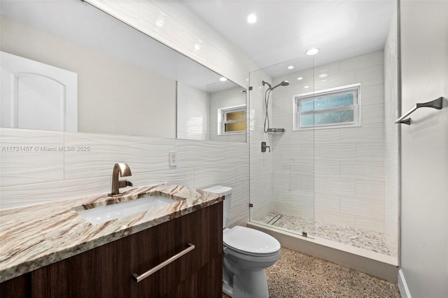 bathroom with tile walls, tiled shower, vanity, tasteful backsplash, and toilet