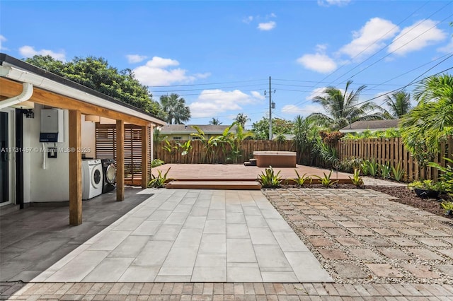 view of patio with a hot tub, a deck, and washer and clothes dryer