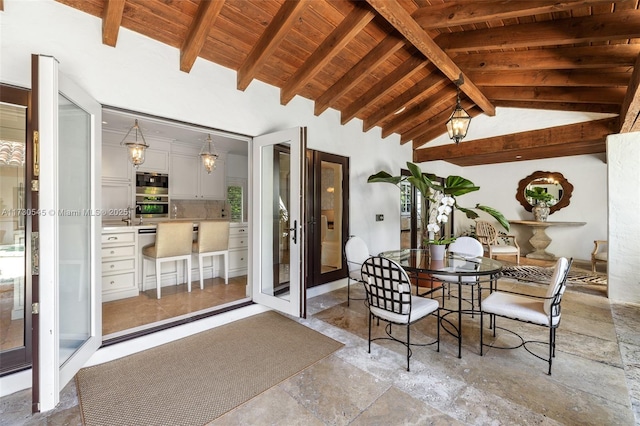 dining space featuring beamed ceiling, high vaulted ceiling, sink, and wooden ceiling