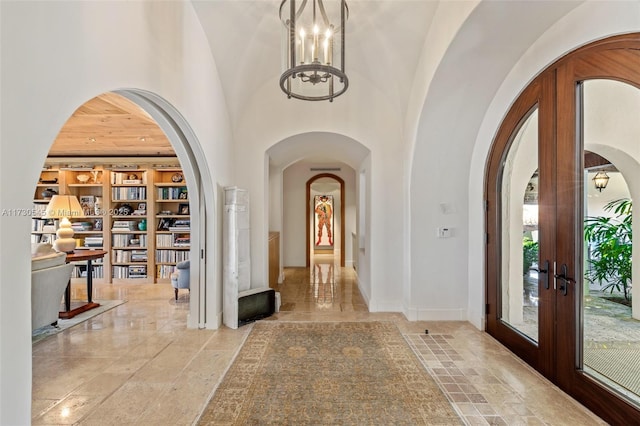 entrance foyer featuring french doors, a towering ceiling, and a notable chandelier