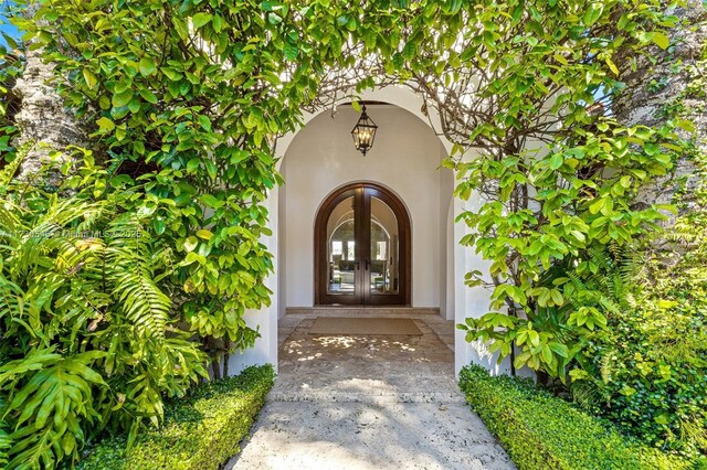 hall featuring high vaulted ceiling, french doors, and a chandelier