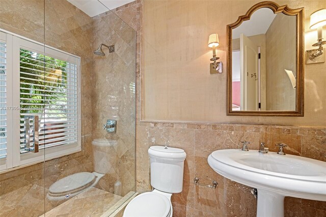 bathroom with toilet, sink, and tile walls