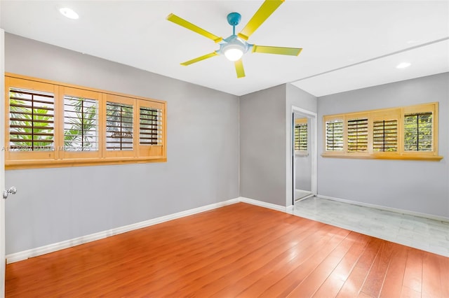 empty room with wood-type flooring, a wealth of natural light, and ceiling fan