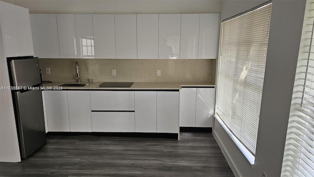 kitchen with stainless steel fridge, sink, white cabinets, and backsplash