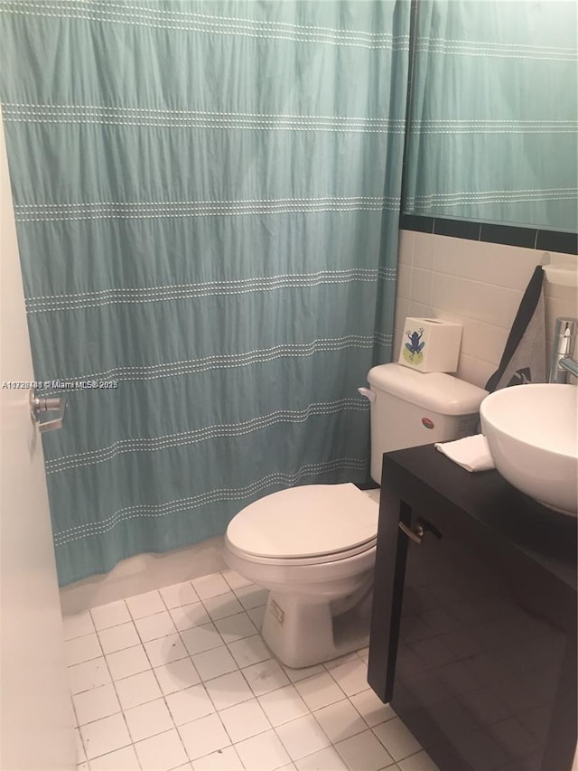 bathroom featuring tile patterned flooring, vanity, tile walls, and toilet