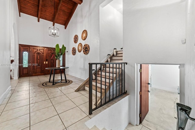 entryway featuring light tile patterned flooring, an inviting chandelier, high vaulted ceiling, wood ceiling, and beam ceiling