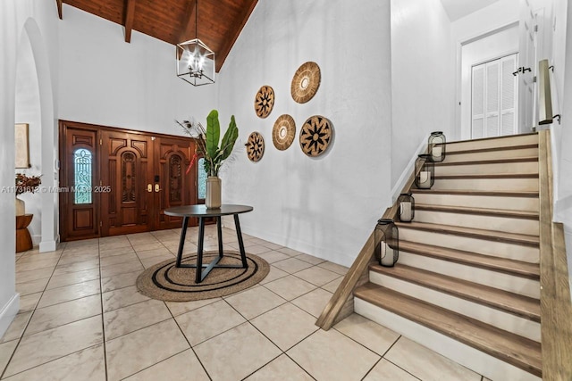 tiled entryway featuring a notable chandelier, high vaulted ceiling, beam ceiling, and wooden ceiling