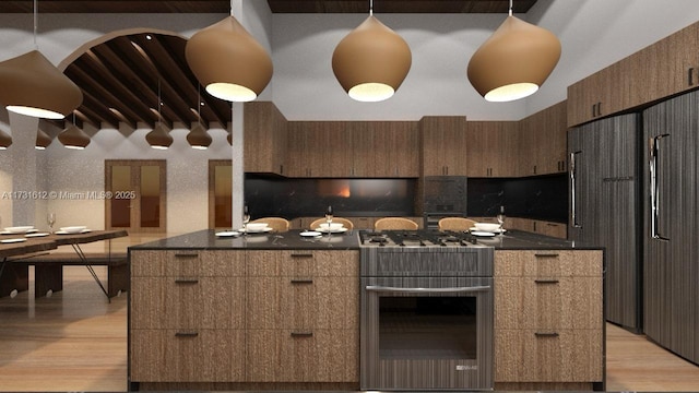 kitchen with stainless steel appliances, pendant lighting, dark stone counters, and light hardwood / wood-style flooring