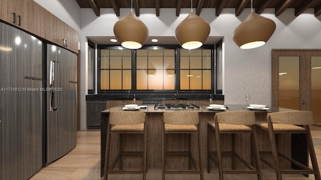 interior space with stainless steel gas stovetop, a breakfast bar area, beamed ceiling, and light wood-type flooring