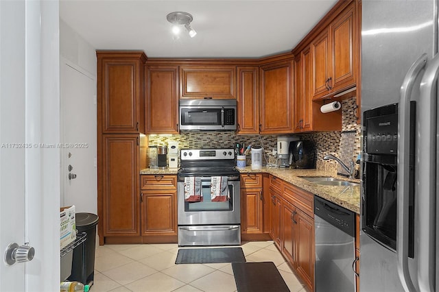 kitchen with light tile patterned flooring, sink, light stone counters, tasteful backsplash, and appliances with stainless steel finishes