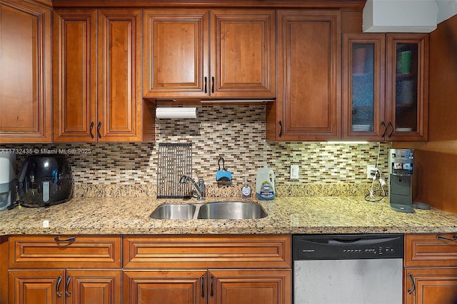 kitchen featuring light stone counters, dishwasher, sink, and decorative backsplash