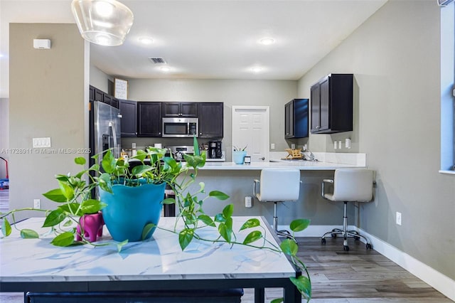 kitchen with appliances with stainless steel finishes, dark hardwood / wood-style flooring, and kitchen peninsula