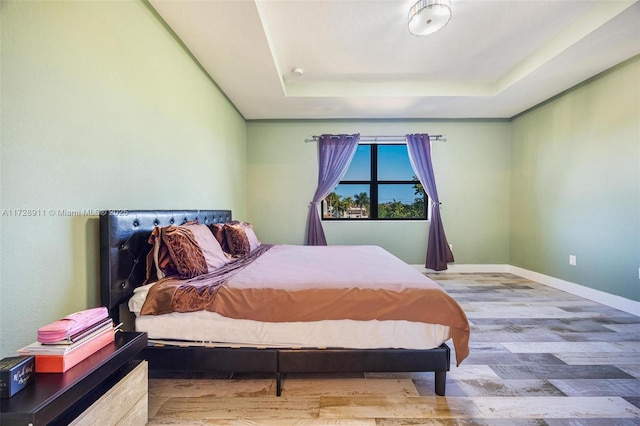 bedroom with a tray ceiling and hardwood / wood-style flooring