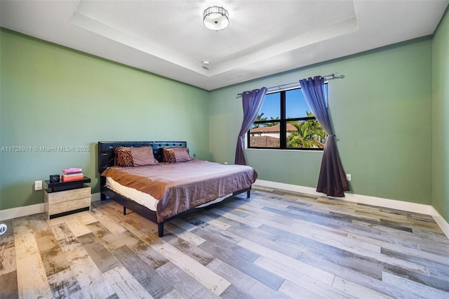 bedroom with hardwood / wood-style floors and a raised ceiling