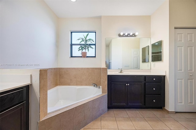 bathroom with tile patterned flooring, vanity, and tiled bath