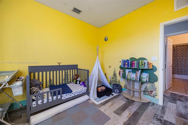 bedroom featuring hardwood / wood-style flooring and a crib