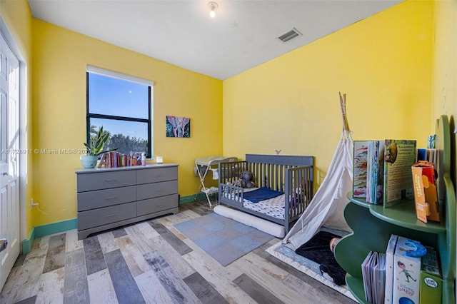 bedroom with a crib and light hardwood / wood-style flooring