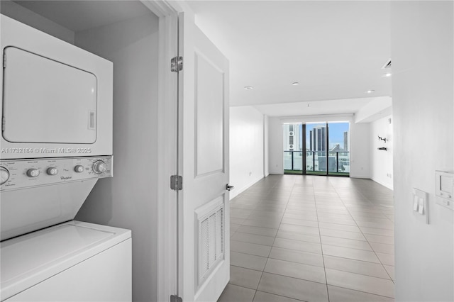 clothes washing area featuring stacked washer / dryer and light tile patterned floors