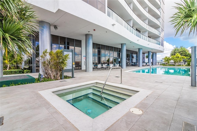 view of swimming pool featuring a hot tub and a patio area