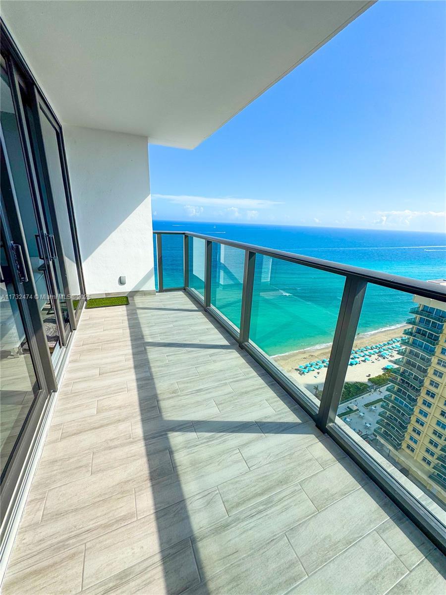 balcony with a water view and a view of the beach