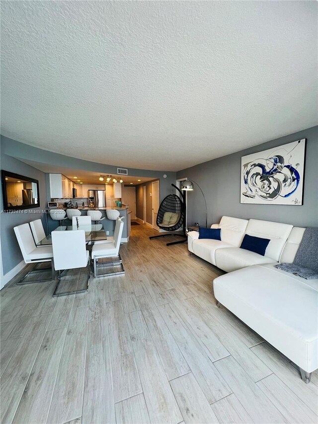 2301 S Ocean Dr Unit 2408, Hollywood, FL 33019 - living room featuring visible vents, a textured ceiling, light wood finished floors, and baseboards