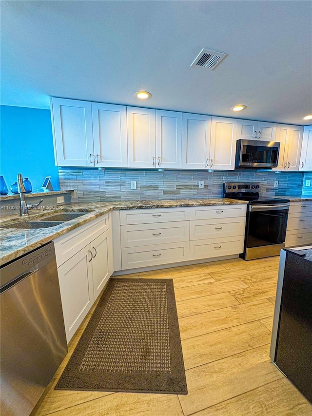 kitchen featuring stainless steel appliances, white cabinetry, and light hardwood / wood-style floors