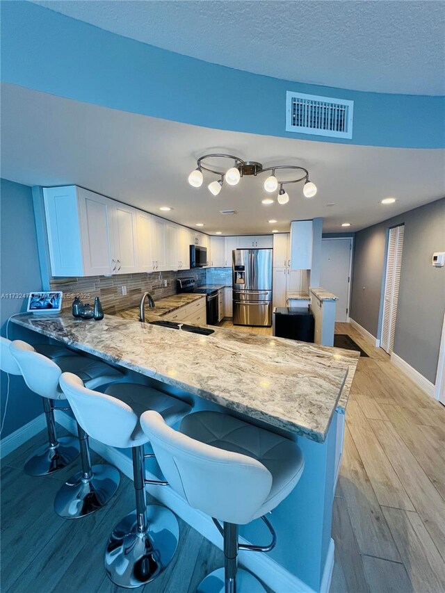 2301 S Ocean Dr Unit 2408, Hollywood, FL 33019 - kitchen with visible vents, baseboards, white cabinets, a peninsula, and stainless steel fridge