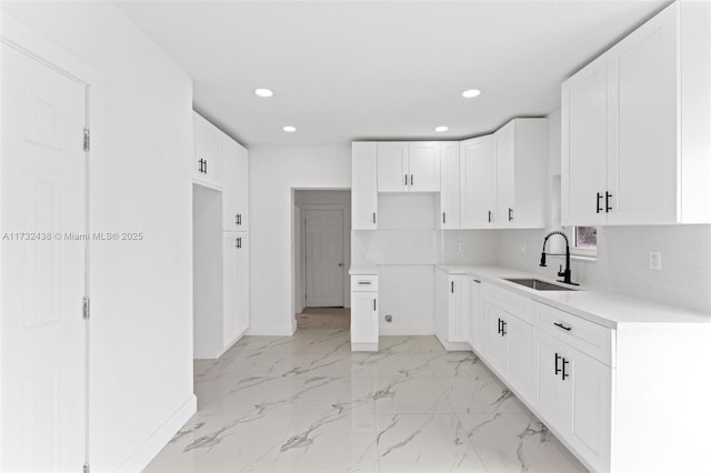 kitchen featuring tasteful backsplash, white cabinetry, and sink