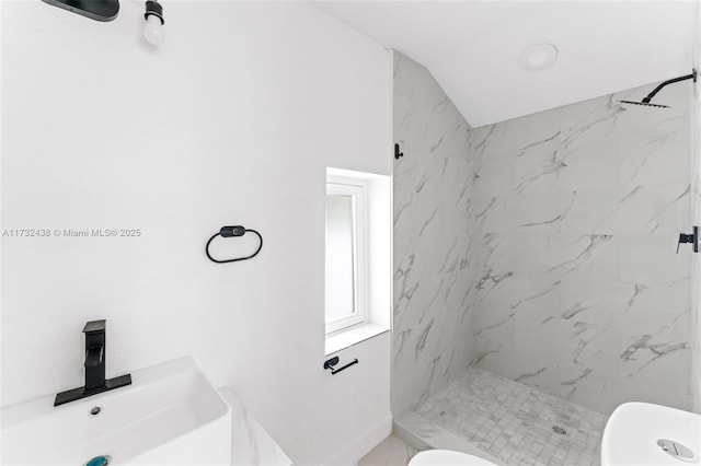 bathroom featuring a tile shower, sink, and toilet