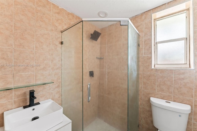 bathroom with a shower with shower door, sink, and toilet